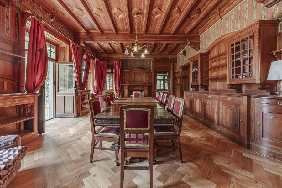 Reception room with timber ceiling and long dining table in Villa Laubenò, offered by Engel & Völkers